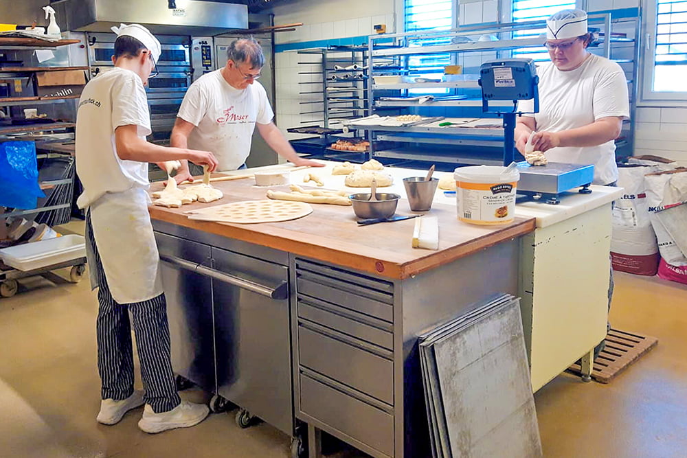 Peter Moser und Auszubildende bei der Arbeit in der Backstube